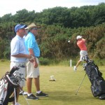 A. Garrett tees off from the tips at Kingsbarns Golf Links as W. Leaman and L. Fedrick look on. — in St Andrews, Scotland.